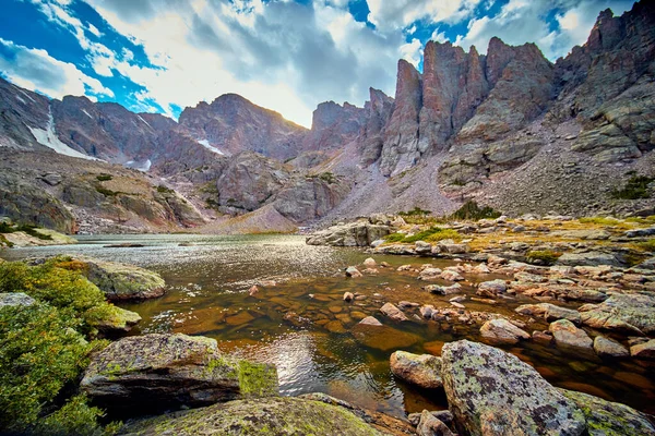 Lago en las montañas rocosas con puntos agudos y nubes — Foto de Stock