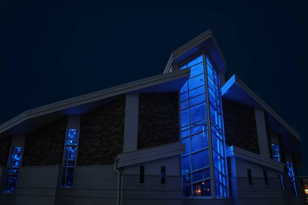 Große verglaste Außenfassade der Kapelle nachts blau beleuchtet — Stockfoto