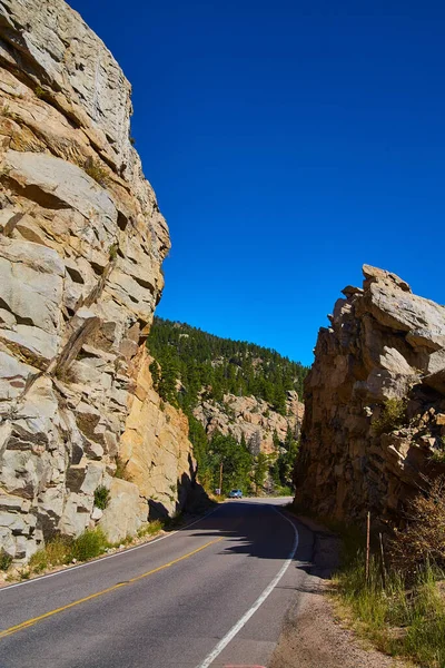Дорога, що проходить через великі скелі в горах проти синього неба. — стокове фото