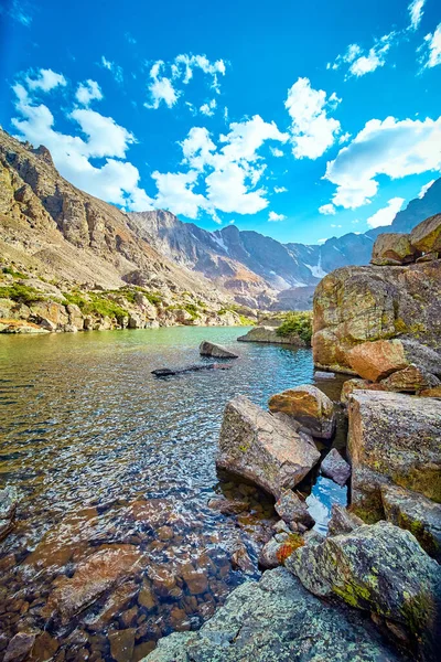 Lago en las montañas rodeado de rocas cubiertas de líquenes — Foto de Stock