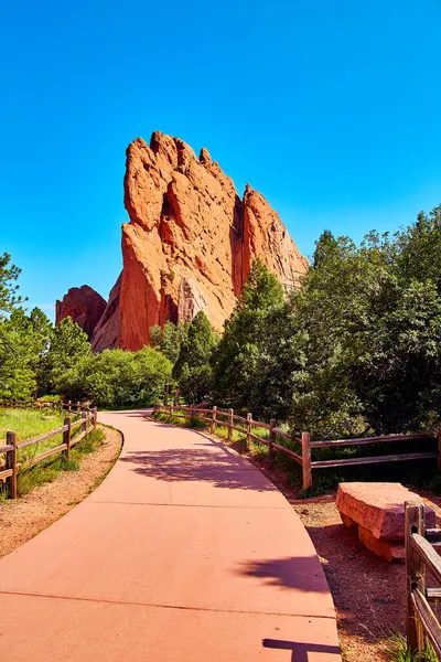 Caminho do parque pavimentado com bancada de pedra e fundo de grande pilar vermelho de rocha — Fotografia de Stock