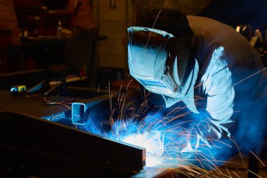 Kaynak yapan metal işçisi portakal kıvılcımları kullanıyor.