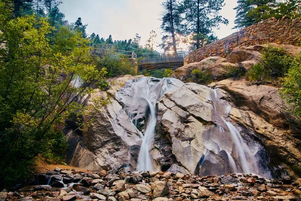 Grande cachoeira sobre rochas com ponte a pé — Fotografia de Stock