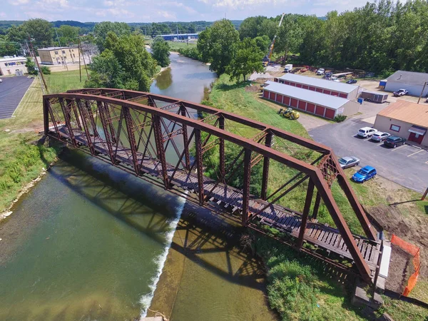 背景に木がある川を渡る茶色のオレンジ色の錆びた金属製の橋の空中ショット — ストック写真