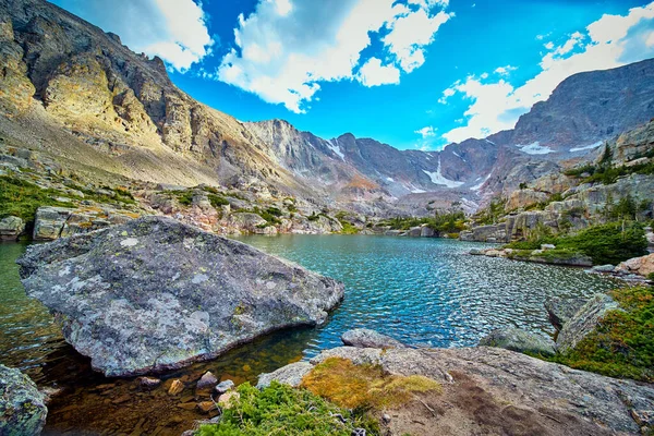 Grande masso di licheni che riposa nel lago circondato da montagne rocciose — Foto Stock