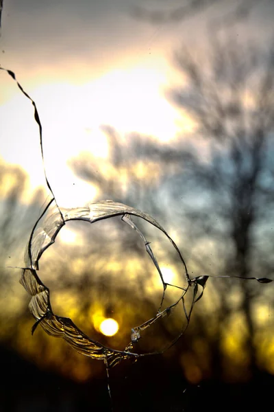 Kırık camların arasından odaklanmamış günbatımı sahnesi — Stok fotoğraf