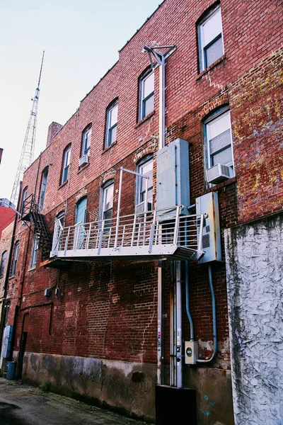 Zadní část budovy v centru města pokrytá cihlami s kovovým schodištěm — Stock fotografie