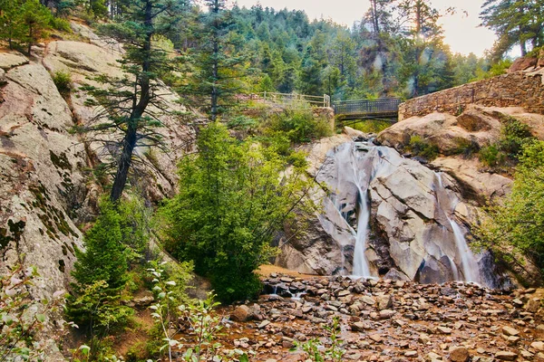 Séta híd vízesés felett kő sziklák a hegyekben — Stock Fotó