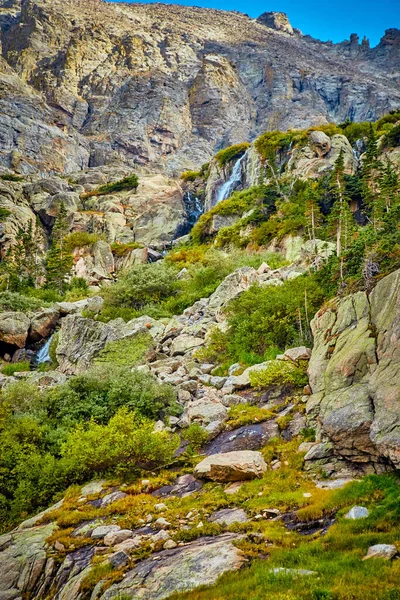 Cascata sulle montagne rocciose con verde lussureggiante — Foto Stock