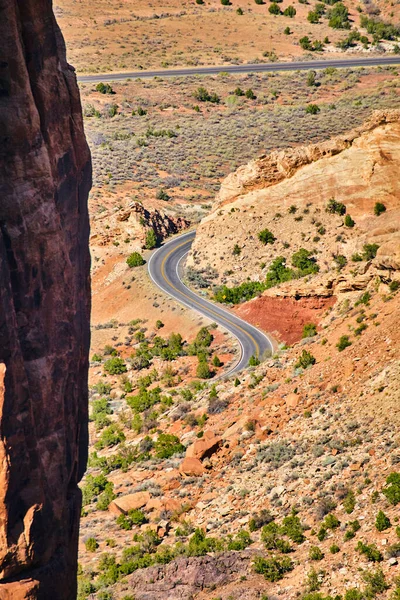Vertikale Felswand mit einer Straße, die sich durch Berge in der Wüste schlängelt — Stockfoto