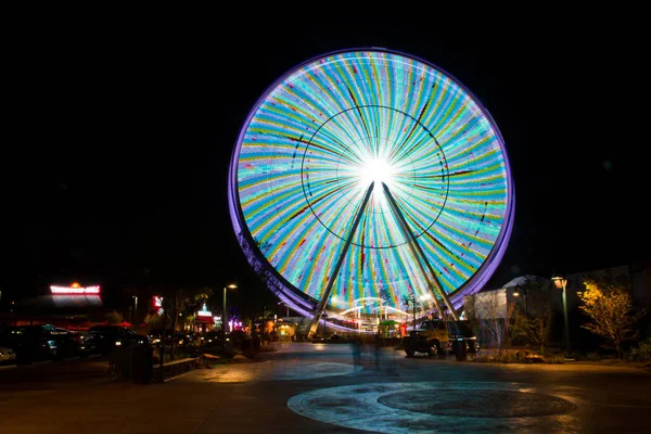 Grande roue la nuit entièrement éclairée de violet et de vert bleus — Photo