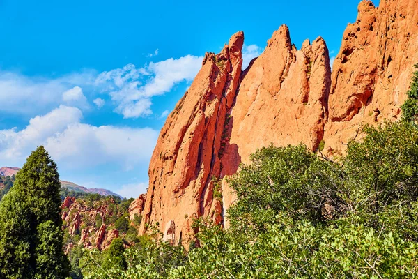 Yeşil ormanlı kırmızı kaya tabakalarından oluşan dağ manzarası — Stok fotoğraf