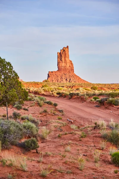 Dirt Road and fence in desert next to large red rock pillar — Stock Photo, Image