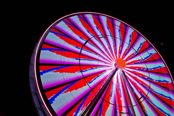 Roda gigante iluminada à noite com vermelhos azuis cinzentos e roxos — Fotografia de Stock