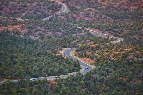 Camino de asfalto serpentea su camino a través de árboles y tierra arenosa roja — Foto de Stock