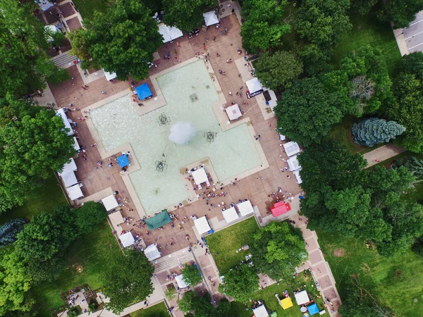 Aérea de una gran piscina rodeada de árboles con carpas de colores sobre el hormigón que rodea la piscina — Foto de Stock