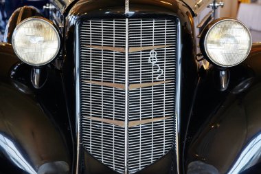 Uzun ön ızgarası ve göz gibi iki ışığı olan antika bir arabanın yakın çekimi.