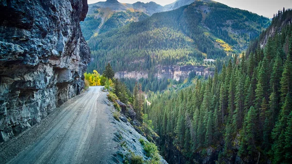 Peligroso camino de tierra en las Montañas Rocosas en el borde estrecho del acantilado en el valle de las montañas — Foto de Stock