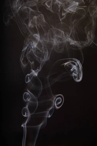 Delicado curling humo gris sobre un fondo negro — Foto de Stock