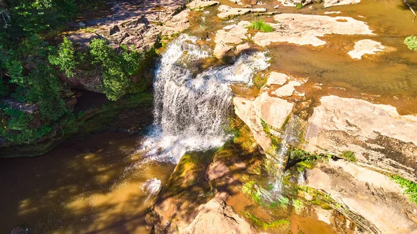Крупним планом водоспад зверху з коричневою водою і мохоподібними коричневими каменями — стокове фото