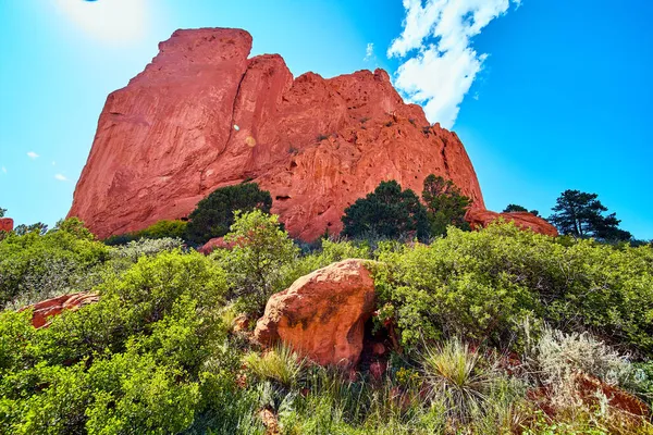 Çöldeki kırmızı kayanın ayrıntıları. Arka planda büyük kırmızı kaya dağı ve güneşli mavi gökyüzü. — Stok fotoğraf