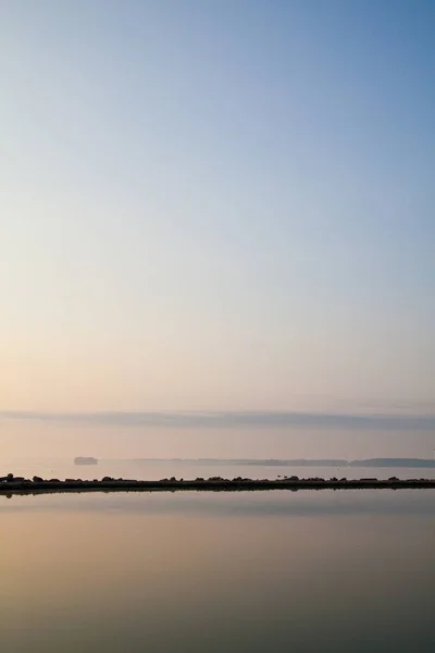 Cena de lago pacífica onde um afloramento rochoso é espelhado nas águas calmas — Fotografia de Stock