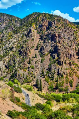 Büyük kanyonun dibinde arabası ve dağ kayalıkları manzaralı bir yol.