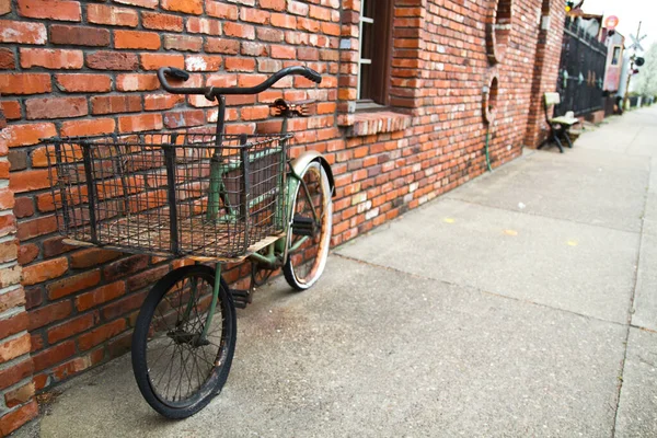 Grünes Fahrrad mit schwarzem Korb auf einem Bürgersteig neben einem roten Backsteingebäude in Louisville — Stockfoto