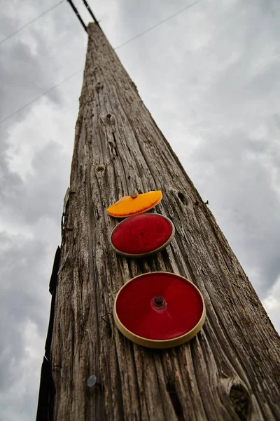 El poste del teléfono con luces rojas y naranjas reflectantes se extiende en un cielo gris — Foto de Stock