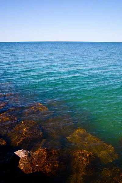 Brązowe skały czają się pod powierzchnią spokojnego jeziora lub oceanu — Zdjęcie stockowe