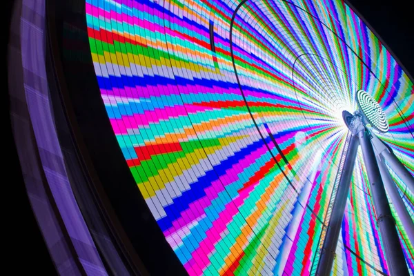 Wormser Blick auf ein Riesenrad, das in einer regenbogenfarbenen Melange aufleuchtet — Stockfoto