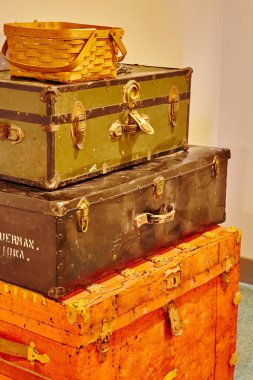 Üç antika sandık yığını, kırmızı, siyah ve yeşil, üstünde sarı ışıklı bir sepet.