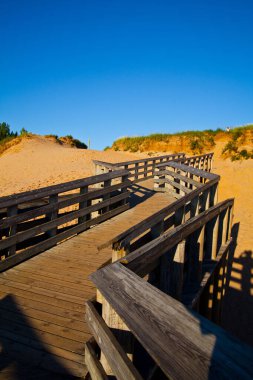 Kum tepelerini aşıp mavi gökyüzüne zigzag çizen tahta köprü.