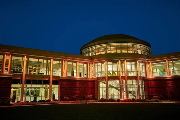 Přední pohled na kolej na univerzitě dobře osvětlené v noci se spoustou oken — Stock fotografie
