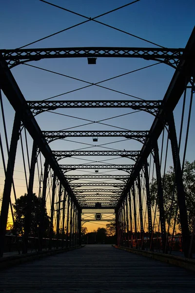 Puente de metal se extiende en la distancia, silueta por el sol poniente naranja —  Fotos de Stock