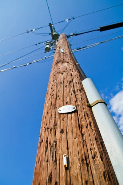 Brun trä telefonstolpe sträcker sig in i en klarblå himmel — Stockfoto