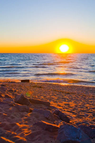 Pomarańczowy i żółty zachód słońca z łagodną wodą i piaszczystym brzegiem plaży — Zdjęcie stockowe