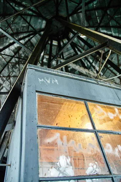 Worms vista de olho de uma cabine dentro de uma torre com feixes de apoio que conduzem para cima, mas cabine é iluminada com luz laranja — Fotografia de Stock