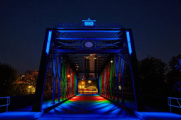 Metallbrücke, die nachts in die Innenstadt führt, beleuchtet von bunten Lichtern — Stockfoto