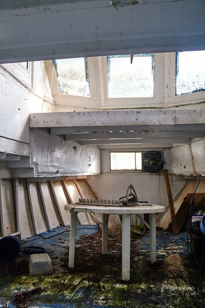 Заброшенная комната с белыми стенами и окнами и белым столом со странной металлической скульптурой на столе — стоковое фото