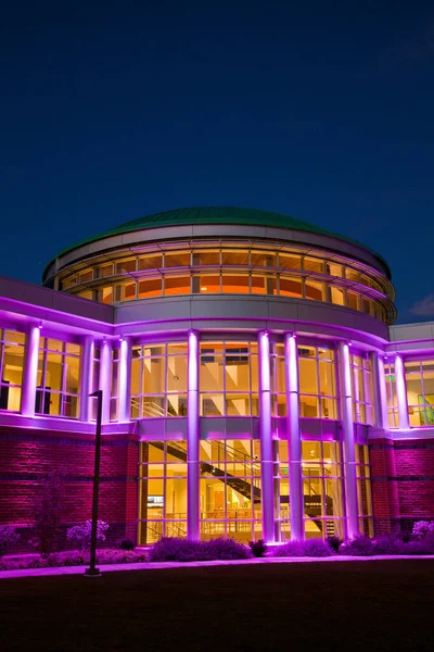 夜幕降临时，许多窗户亮起紫色，正对着现代建筑的前门拍摄 — 图库照片