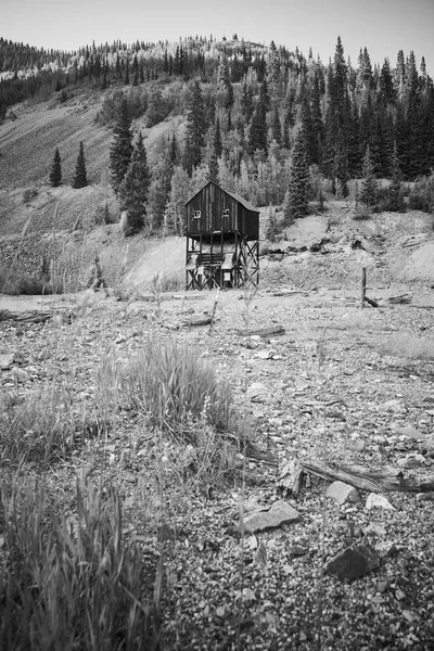 Black and white of desert field and mountains with mining building in distance