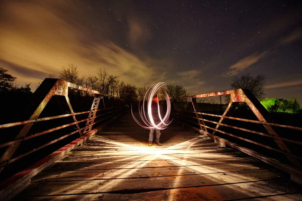 Bílé vířící světlo na kovovém mostě, které za soumraku dopadá na samotný most. — Stock fotografie