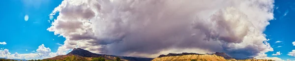Panorama dużego pasma górskiego przeciwko ogromnym chmurom burzowym pokrywającym góry w cieniu — Zdjęcie stockowe