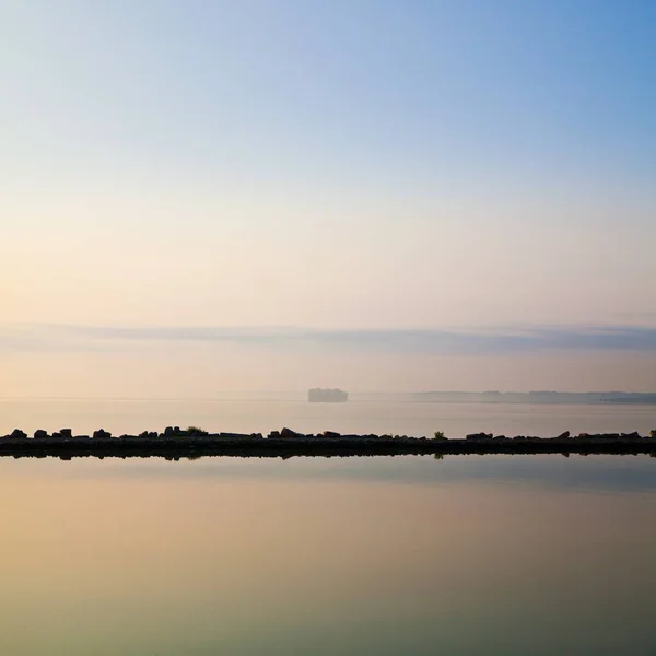 Мирная сцена у озера, где скалистый горизонт отражается на тихих водах — стоковое фото