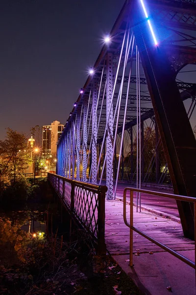 Metallbrücke, die in eine Stadt führt, leuchtet nachts lila — Stockfoto