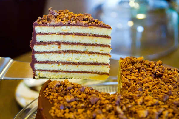 Bolo branco de seis camadas com cobertura de chocolate e nozes no topo com uma grande peça cortada para exibição — Fotografia de Stock