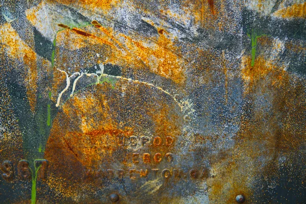Placa metálica vieja oxidada con letras y números grabados en el fondo —  Fotos de Stock
