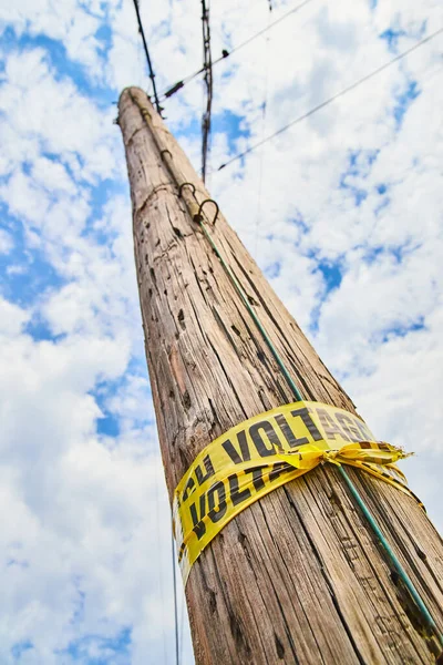 나무로 된 전봇대를 올려다보고 있는 노란불 경보 테이프 — 스톡 사진