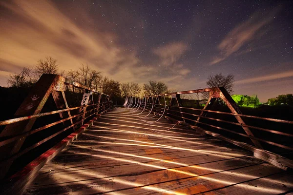 Perspektiva záběru bílého světla se rozléhá po kovovém mostě za soumraku — Stock fotografie